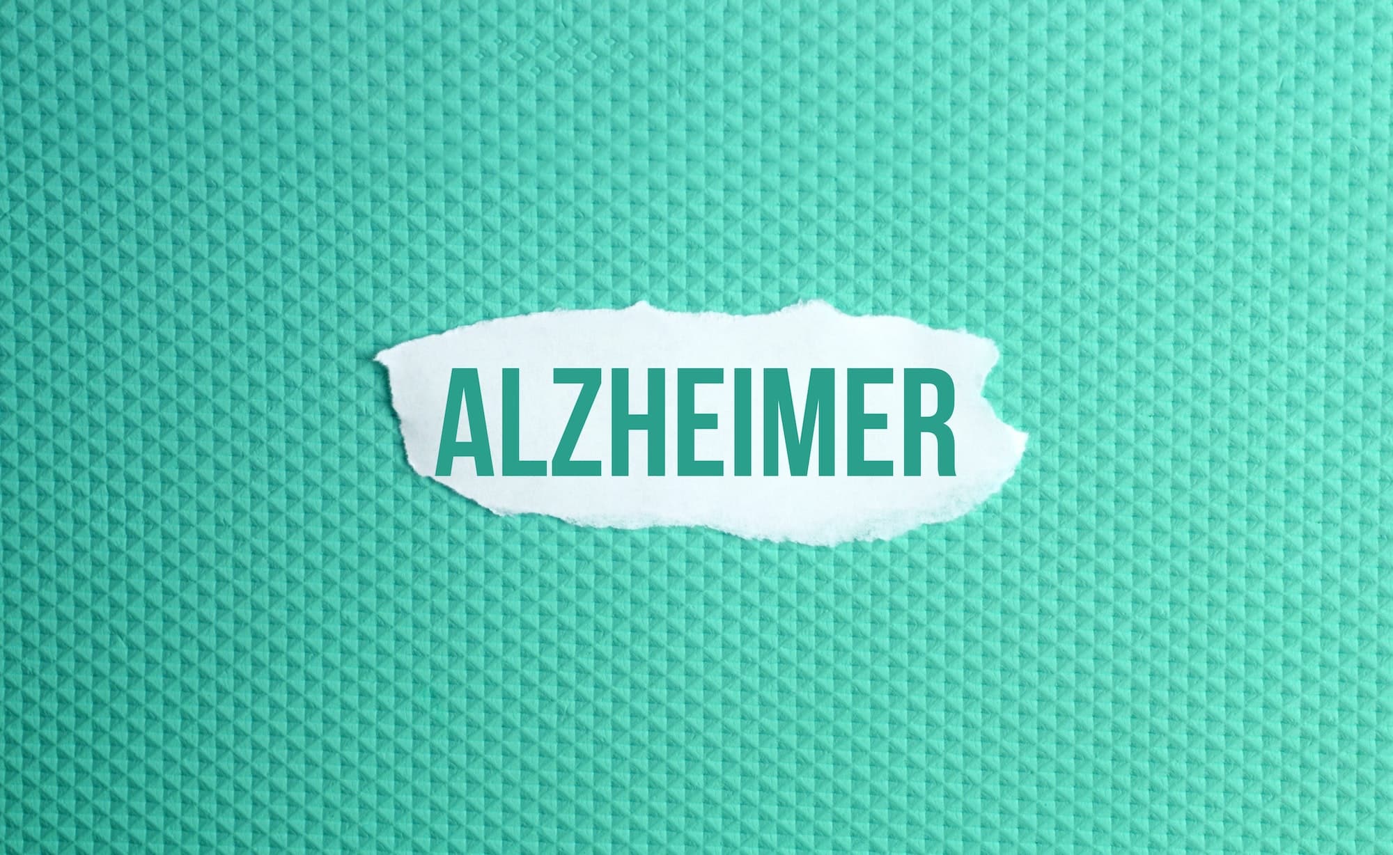 a torn paper written with inscription Alzheimer on a green background