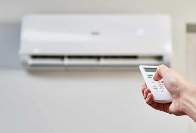 Hand adjusting temperature on air conditioner