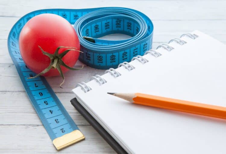 Measuring tape and notebook with juicy tomatoes, the concept of healthy eating and losing weight