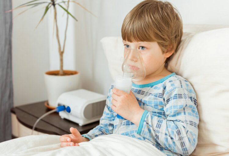 Boy with a respiratory syncytial virus, inhaling medication through an inhalation mask. Flu