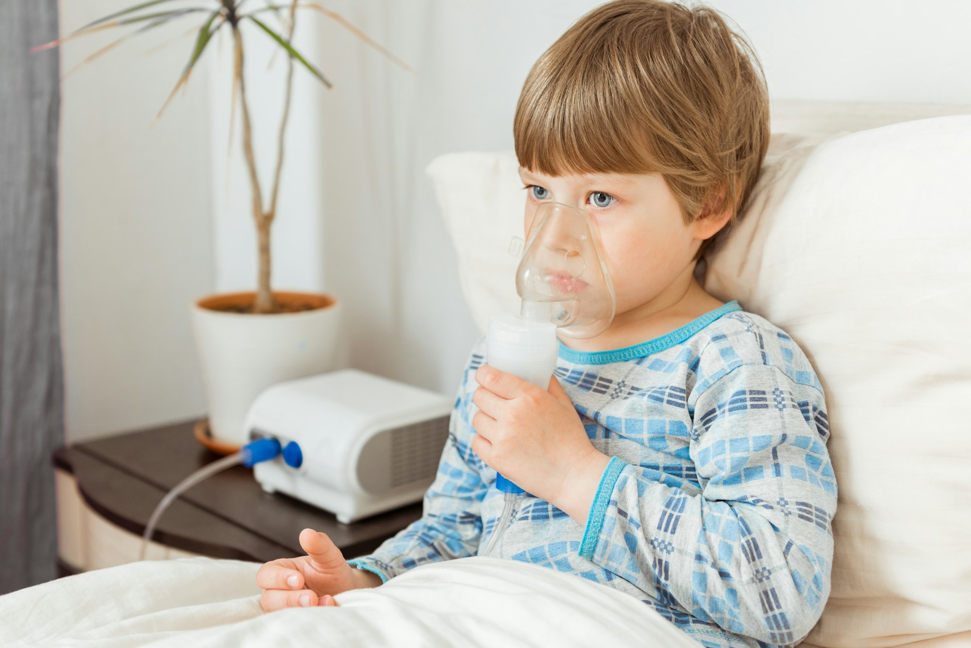 Boy with a respiratory syncytial virus, inhaling medication through an inhalation mask. Flu