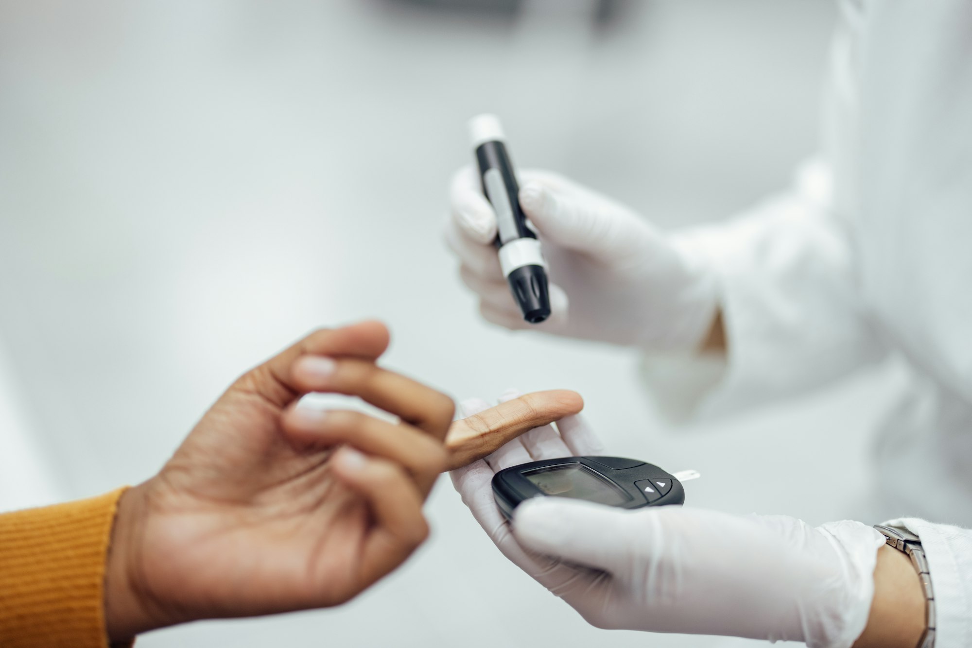 Close-up image of a doctor using blood glucose test kit.