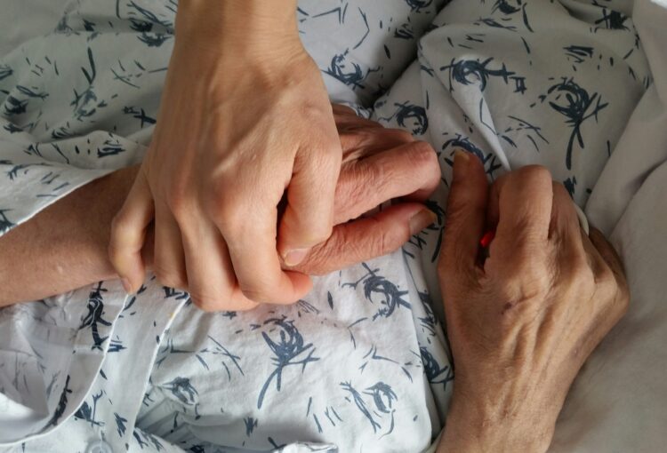 holding elderly family member's hand in hospital during end of life care