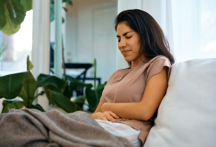 Woman with stomach pain on the sofa at home.